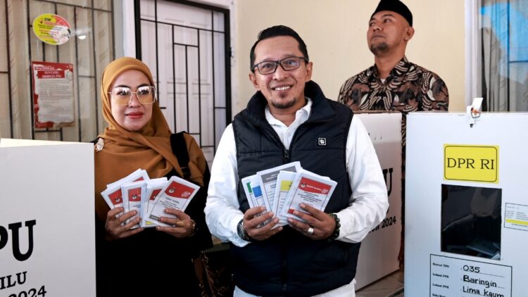 MENCOBLOS— Bupati Eka Putra bersama istri Ny Lise Eka Putra saat pencoblosan Pemilu 2024 di TPS 35, Jorong Diponegoro, Nagari Baringin, Kecamatan Limo Kaum.