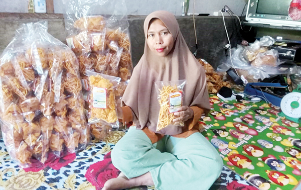 BISNIS RUMAHAN— Yusneti (37), warga Bukik Ngalau, Kelurahan Batugadang, Kecamatan Lubukkilangan, melakukan packaging kemasan kue bawang “Tiga Saudara”, sebelum dimasukkan ke sejumlah toko, kedai serta swalayan dan supermarket di Kota Padang. Usaha yang dirintis sejak dua tahun terakhir ini terus berkembang setelah mendapat bantuan dari UPZ PT Semen Padang.