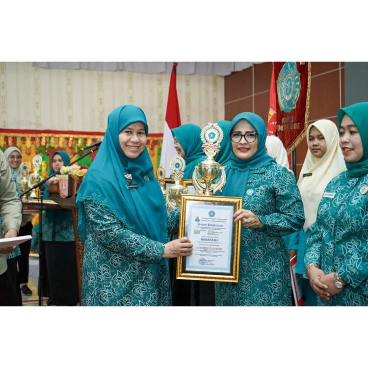 PIAGAM PENGHARGAAN— Ketua TP-PKK Kabupaten Solok Selatan Ny. Hj. Erniati Khairunas lihatkan penghargaan bersama Ketua TPK PKK Sumbar Harneli Mahyeldi.