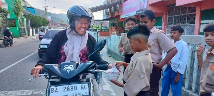 BAGIKAN TAKJIL— Murid SD Negeri 3 Padang Panjang Barat (PPB) melakukan pembagian takjil kepada warga sekitar yang melewati jalan di depan sekolah mereka, Rabu (20/3).