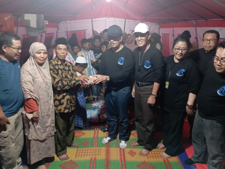 Prof Yulius memasangkan kain sarung pada salah seorang anak korban banjir bandang, ditenda pengunsian, di Jorong Tiga Batur, Nagari Parambahan. (chandra antoni)