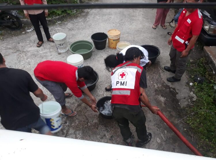 DISTRIBUSIKAN AIR BERSIH—Terlihat tim  PMI saat distribusikan air bersih pada warga dan korban banjir bandang.