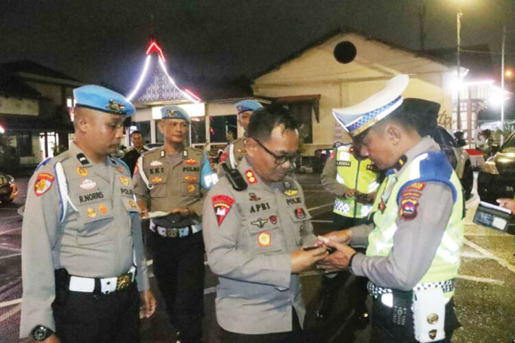 Periksa telepon— Wakapolresta Bukittinggi AKBP Apri Wibowo memeriksa telepon genggam milik personel kepolisian untuk memastikan petugas tidak terlibat dalam praktik judi online, Minggu (16/6) malam.