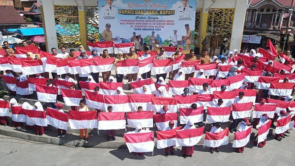 USAI— Wakil Bupati Solok Selatan H. Yulian Efi berfoto bersama ratusan pelajar sambil memegang bendera merah putih usai kegiatan penyerahan seragam untuk siswa baru Kecamatan Sangir di RTH Solok Selatan,
Selasa (23/7).