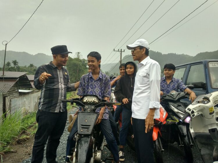 BINCANG-BINCANG— Bupati Safaruddin dan anggota DPRD Limapuluh Kota Prima berbincang-bincang dengan anak sekolah lewat jalan yang baru diperbaiki, anak-anak tampak tersenyum.