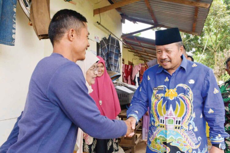 BERIKAN BANTUAN— Bupati Agam Andri Warman memberikan bantuan sekaligus peletakan batu pertama
bedah rumah milik Mulyadi warga Jorong III Kampuang, Nagari Gadut, Kecamatan Tilatang Kamang.