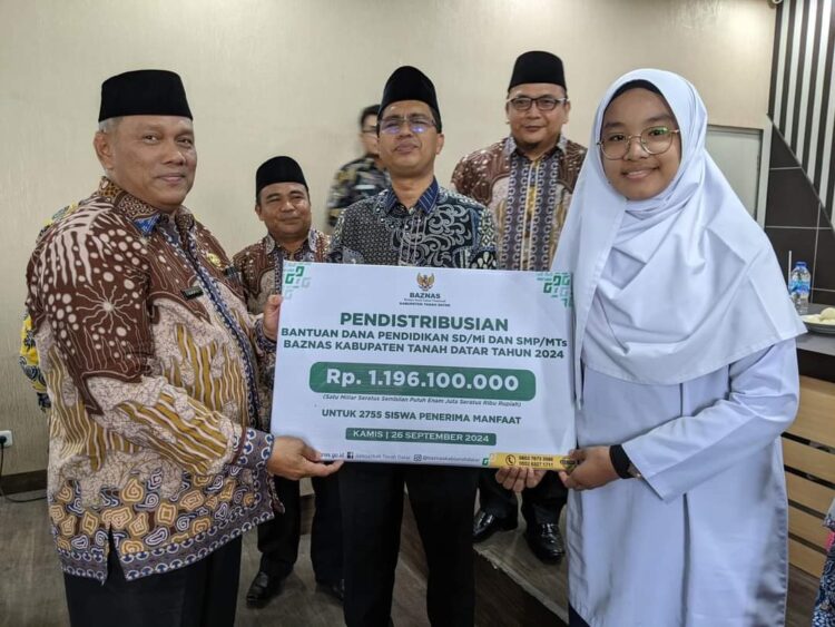 BANTUAN—Kankemenag Tanahdatar H.Amril menyerahkan bantuan pada salah seorang siswa.