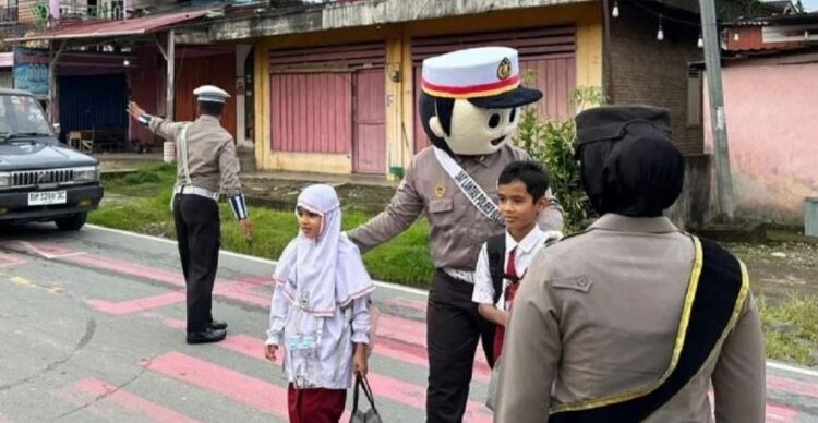 SERAGAM BADUT—Petugas Kepolisian Polres Solok Selatan menggunakan seragam badut membantu pelajar menyeberangi jalan.