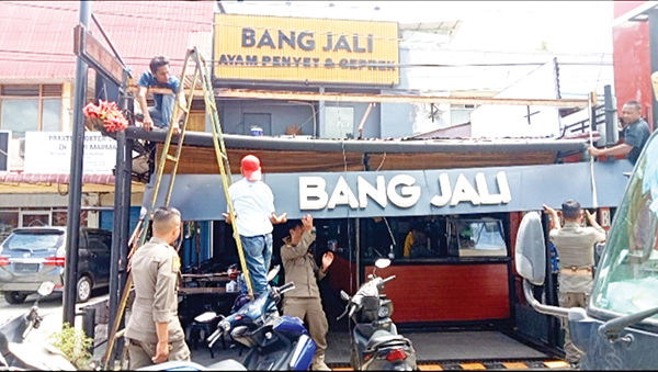 PENERTIBAN REKLAME— Tim dari Badan Pendapatan Daerah (Bapenda) Kota Padang, melakukan penertiban iklan reklame dari berbagai macam merek dagang dan perusahaan yang tidak tertib membayar pajak, Kamis (17/10) pagi.