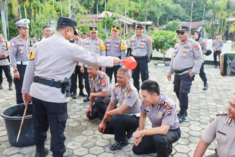 MANDI KEMBANG—Kapolres Sawahlunto AKBP Purwanto Hari Subekti,  saat menyirami air dengan kembang pada poersonel yang naik pangkat.