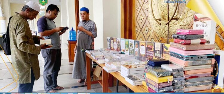 JUALAN BUKU KELILING— Pedagang buku Irfan Rifai sedang melayani pembeli buku yang dijualnya di pelataran Masjid Agung Manarul ‘Ilmi Islamic Centre, Jumat (10/1) pagi.