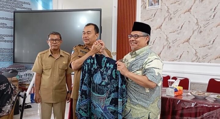PENYERAHAN—Ketua DPRD Sumbar, Muhidi secara simbolis baju batik untuk para guru kepada Kepala SMAN 10 Padang, Muhammad Isya.